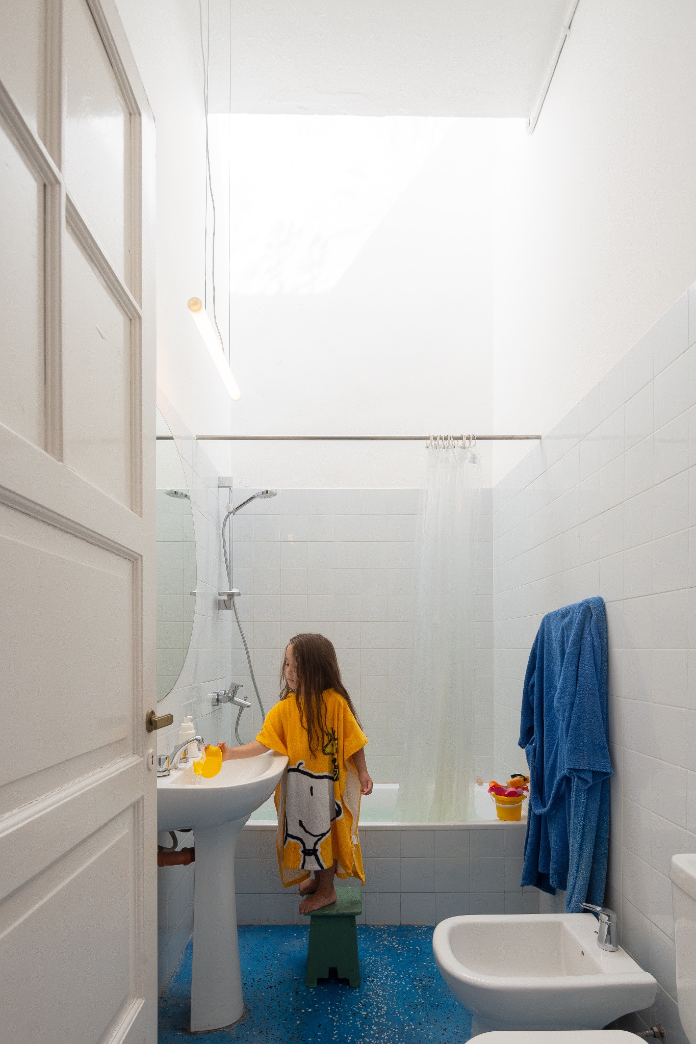 Baño blanco con iluminación cenital y piso azul