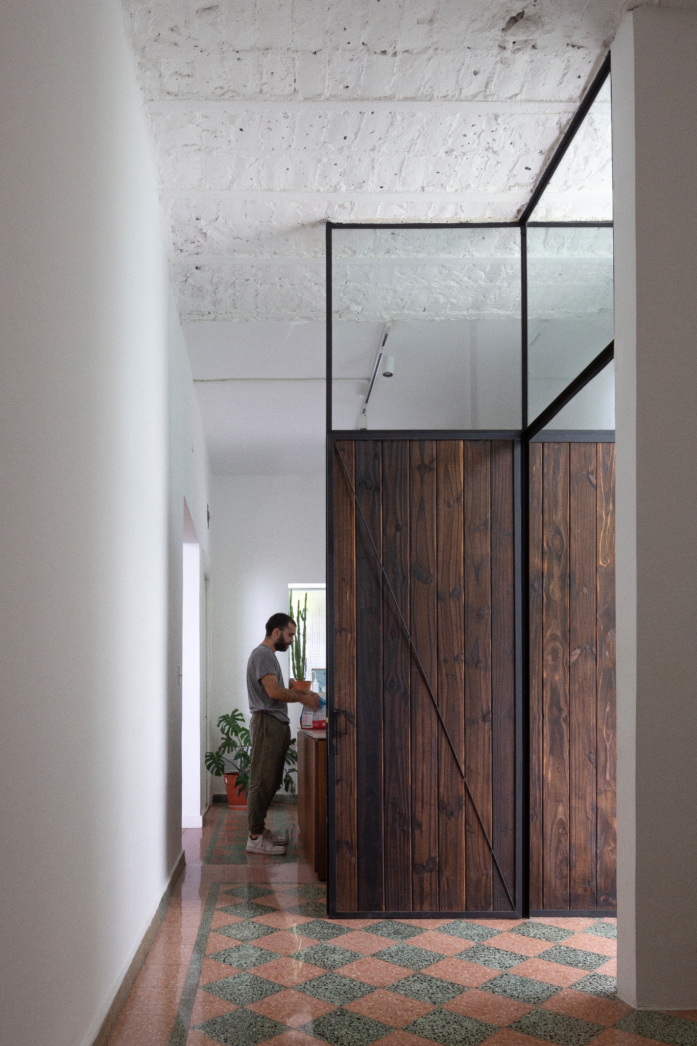 Interior con piso de mosaico y un cerramiento alto de madera y vidrio