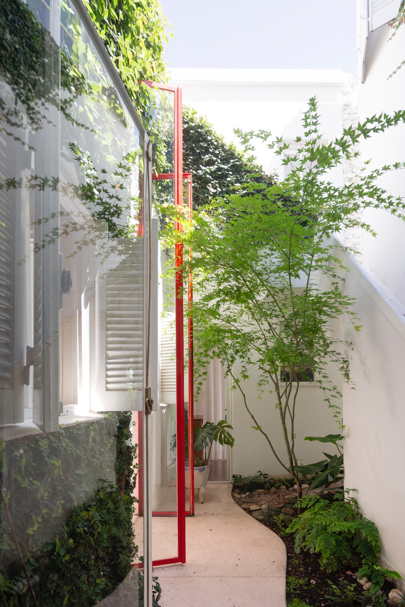 Carpintería roja abierta hacia un patio con vegetación