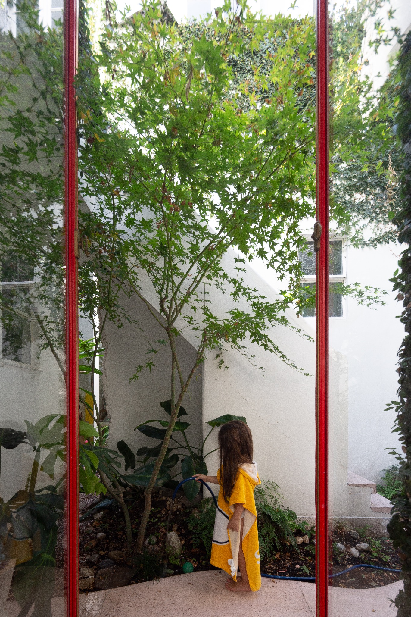 Patio interior visto a través de una carpintería roja