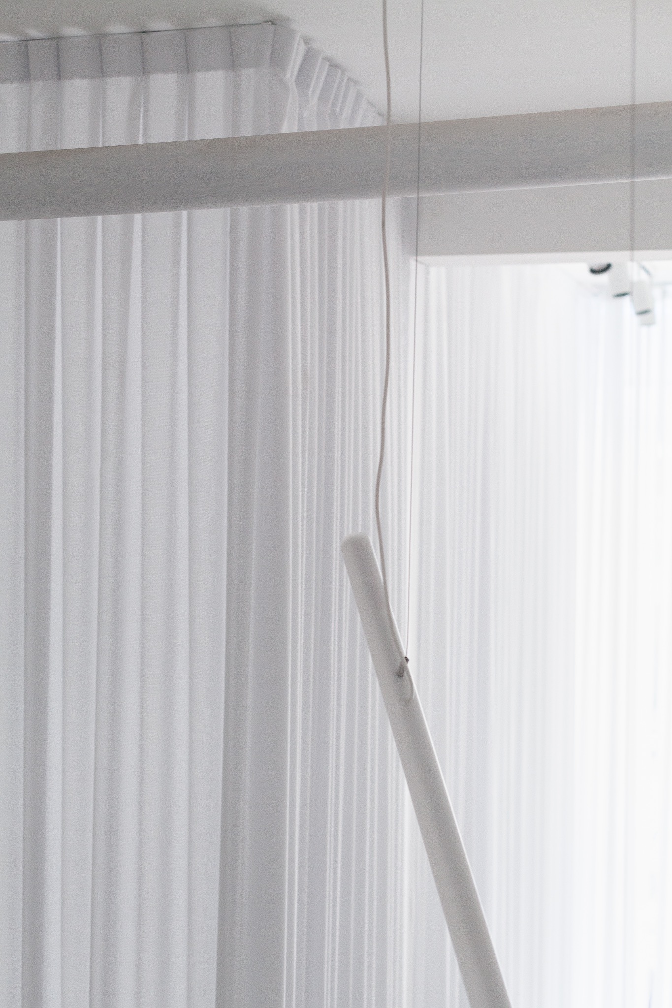 Detalle del tensor y las luminarias entre cortinas blancas